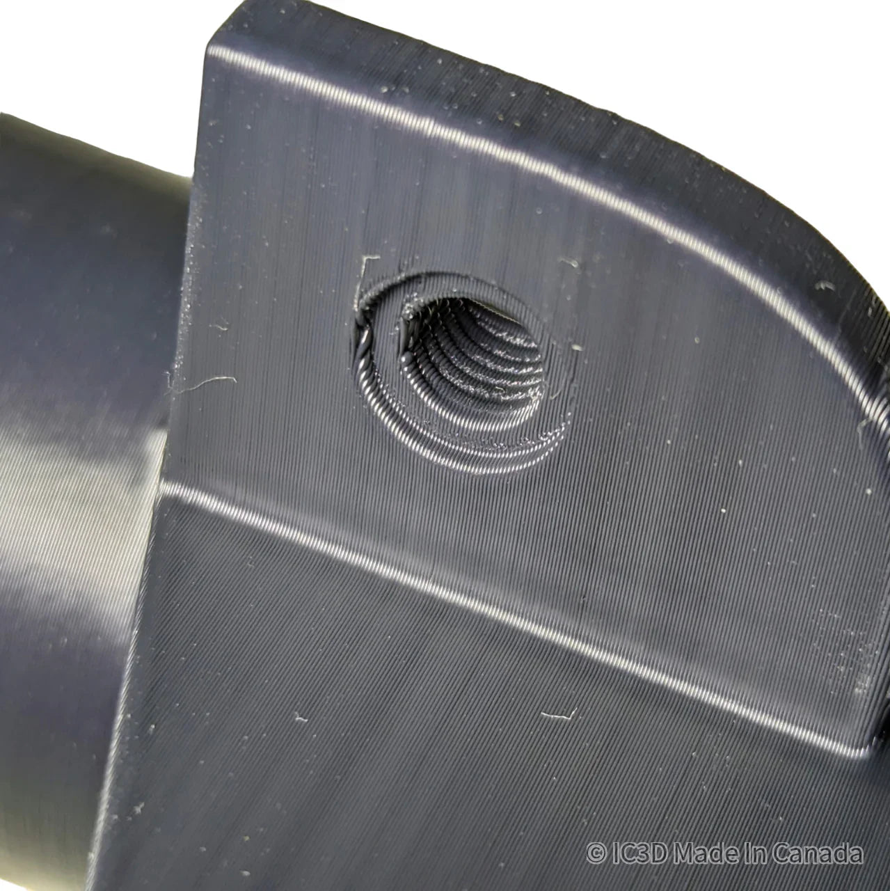 Close-up of a black 3D printed part with a threaded hole, visible layer lines